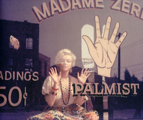 Photo of Marilyn Munroe, hand against the window of a Palmist’s shop. There’s a cartoon hand painted on the window.