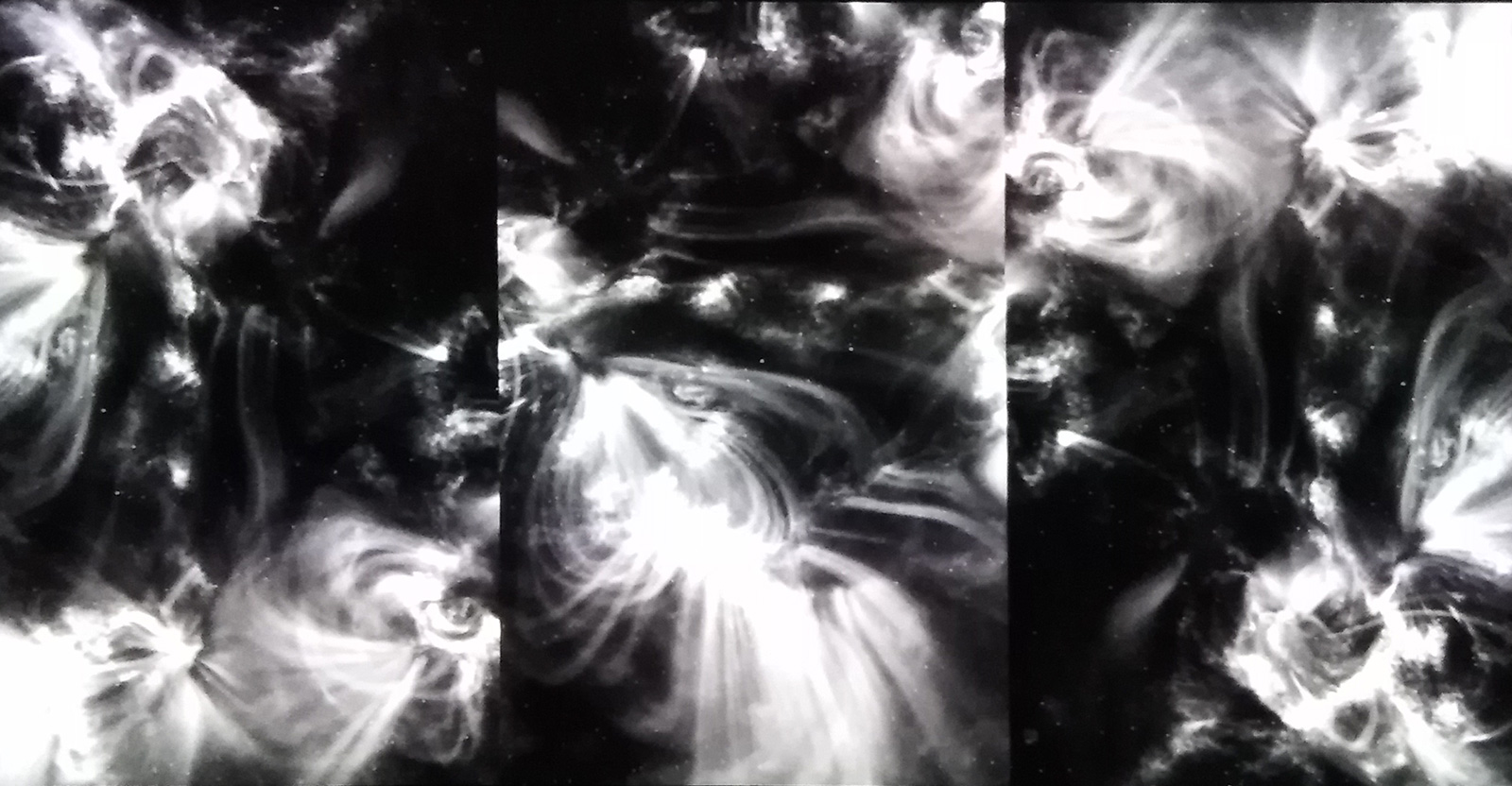 A three panel blakc and white abstract video image of swirling forces.